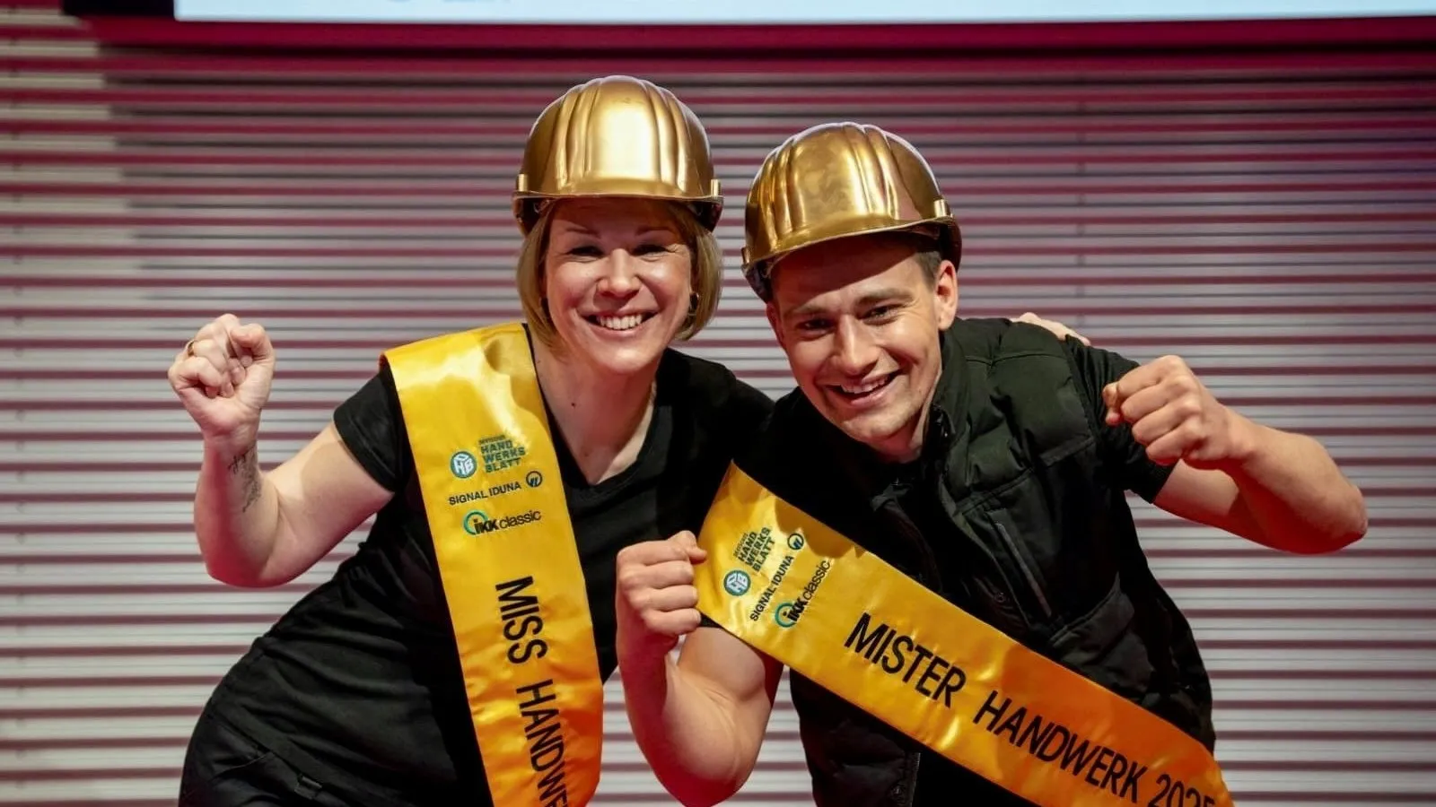 Katja Lilu Melder und Marius Karl Hanten tragen ihre gelben Schärpen und goldenen Helme und freuen sich über ihre Auszeichnung.